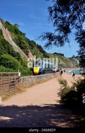 People on the seawall watching an Intercity Express Train passing red sandstone cliffs at Sprey Point, Teignmouth, South Devon. Stock Photo