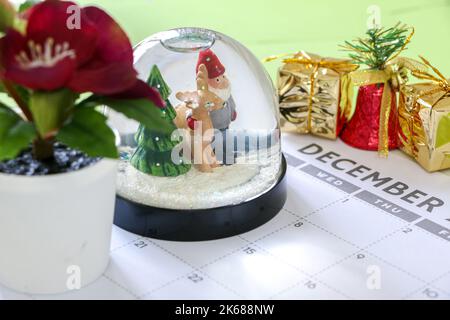 Christmas concept, festive snow globe and other Christmas decorations on December calendar, Christmas presents, bells and plants Stock Photo