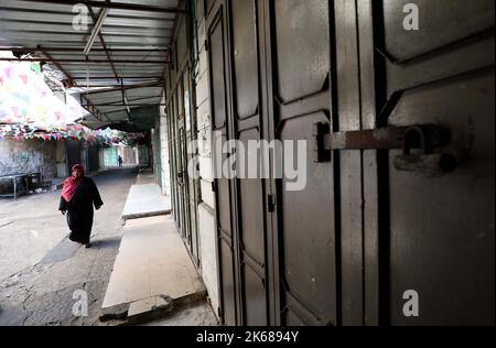 Nablus. 12th Oct, 2022. A woman walks past closed shops in the West Bank city of Nablus, Oct. 12, 2022. TO GO WITH 'Palestinians stage commercial strike in solidarity with Jerusalem refugee camp' Credit: Ayman Nobani/Xinhua/Alamy Live News Stock Photo
