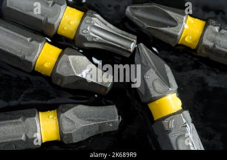 Macro of Multiple Screwdriver Drill Bits with Yellow Band on Wet Dark Background Horizontal Stock Photo