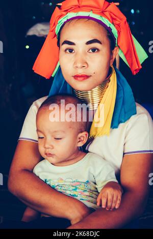 Long Neck Woman is sitting with her child. Tribal village Northern Thailand. Stock Photo