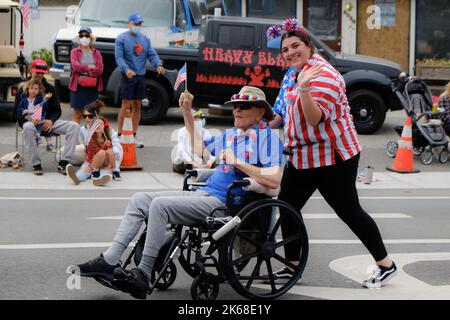 An elderly caucasian man with a young caucasian female caregiver in an independence day parade Stock Photo