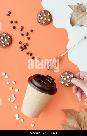 Coffee mug with natural cork. Coffee cup to go on orange white Autumn background with dry leaves. Coffee beans, chocolate cookie in hand and sugar Stock Photo