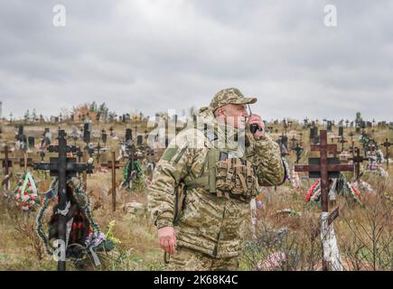 Lyman, Ukraine. 11th Oct, 2022. A Ukrainian soldier is seen standing in a cemetery in Lyman. A burial site was discovered next to the cemetery by the Ukrainians after the city was liberated from Russian troops in Donetsk region. At least 32 Ukrainian soldiers' bodies have been exhumed from a mass grave in Lyman, a city in Donetsk region that was under Russian occupation. Authorities said they were buried together and initial investigation has shown some bodies were blindfolded and tied on the hands, which suggested signs of torture and execution. Another 22 civilians, including children we Stock Photo