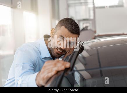 Photo of young smiling man touching and checking new car. Concept for car rental Stock Photo