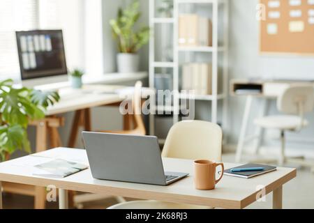 Background image of workplace design with open laptop on table in minimal office interior, white color dominant Stock Photo