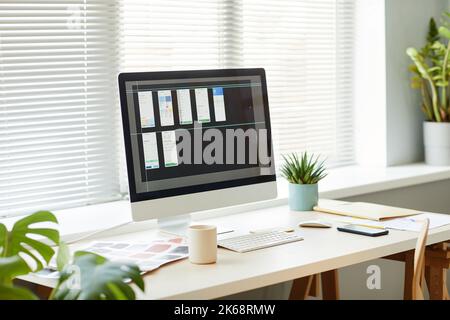 Minimal background image of computer with mobile app designs on screen at workplace table Stock Photo