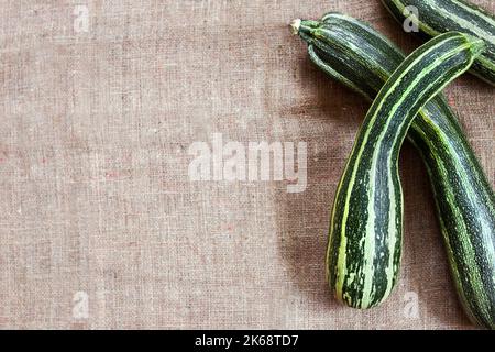 Fresh striped zucchini on sackcloth background with copy space. Flat lay, top view. Rustic style Stock Photo