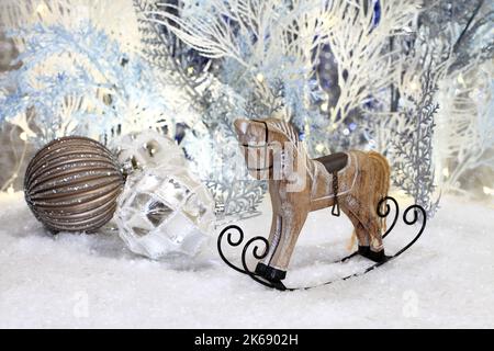 Christmas toys lie on artificial snow against the background of blue and white artificial trees. Closeup. Night studio shooting. Stock Photo