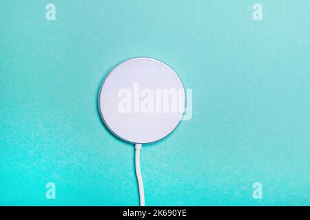 White wireless charging pad for smartphone on the green background. Modern technologies. Stock Photo