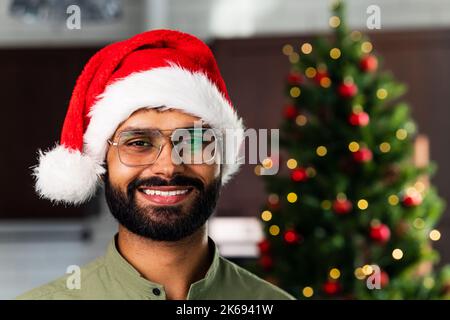 Happy young man wearing santa hat looking at camera celebrating New Year distance online party Stock Photo