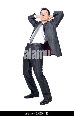 Relaxed businessman in suit standing with hands behind head Stock Photo