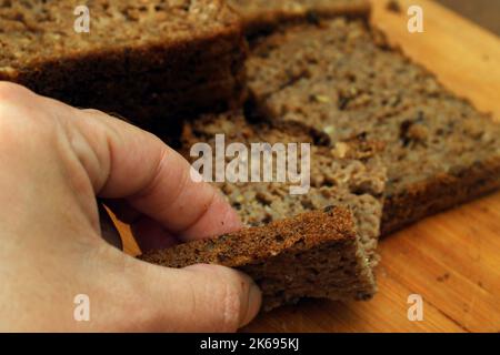 A woman breaks off a piece of whole grain bread. Defocus. Healthy food concept. Stock Photo