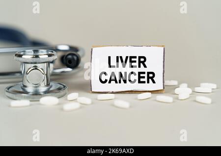 Medical concept. On a gray background, a stethoscope, pills and a cardboard plate with the inscription - Liver cancer Stock Photo
