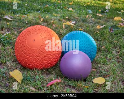 three heavy slam balls filled with sand in a backyard lawn, exercise and functional fitness concept Stock Photo