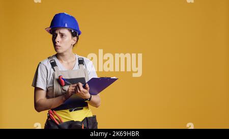 Portrait of construction worker taking notes and doing architecture measurement, writing and brainstorming ideas on clipboard papers. Female architect planning refurbishment project. Stock Photo