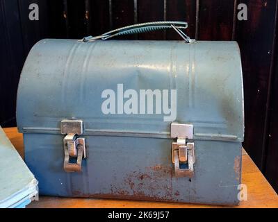 https://l450v.alamy.com/450v/2k69j57/old-dented-blue-metal-lunch-pail-with-a-book-on-a-wooden-table-2k69j57.jpg