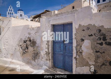 Blue painted wooden entrance doors on distressed white roughcast building, Pyrgos, Santorini, Greece. Stock Photo