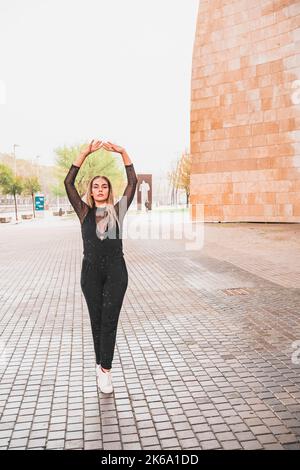Young blonde woman dressed in black dancing in the rain contemporary street dance Stock Photo