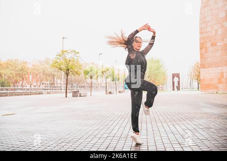 Happy woman dancing in the street under heavy rain Stock Photo