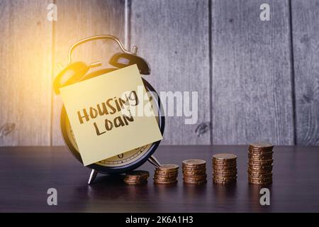 Housing Loan word on yellow sticky note black alarm clock and stacked golden coin Stock Photo