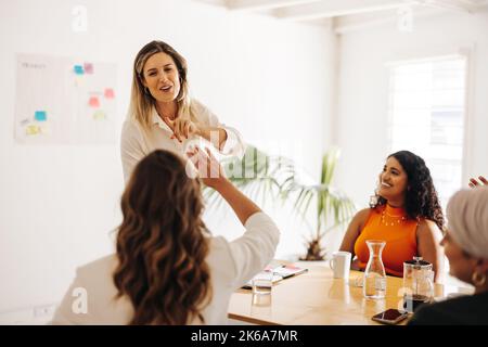 Happy businesswomen high fiving each other during a meeting in a boardroom. Successful businesswomen celebrating their achievement. Diverse businesswo Stock Photo