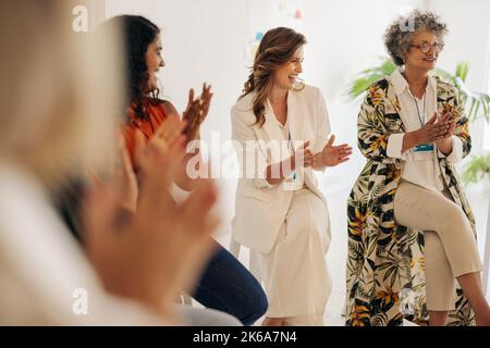 Smiling businesswomen applauding during a conference meeting. Group of multicultural businesswomen celebrating their achievement. Successful businessw Stock Photo