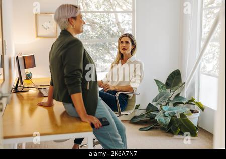 Two young businesswomen having a discussion in a modern office. Creative businesswomen working as a team in a woman-owned company. Stock Photo