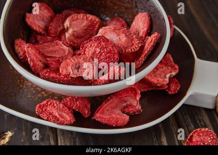 Strawberry chips are stacked in ceramic dish. Hundred-percent natural freeze-dried strawberries. Close up. Healthy vegetable chips Stock Photo