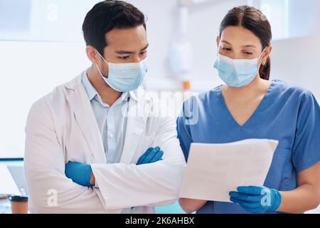 Getting their data up to scratch. a young dentist reading through paperwork with his assistant. Stock Photo
