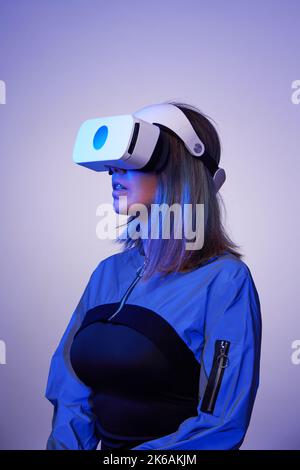 Woman is using virtual reality headset. Concept of virtual, augmented and extended reality, metaverse, entertainment and communication. Stock Photo