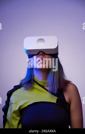 Woman is using virtual reality headset. Concept of virtual, augmented and extended reality, metaverse, entertainment and communication. Stock Photo