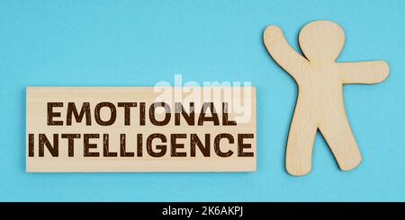 Business concept. On a blue background, a wooden figure of a man and a plate with the inscription - Emotional Intelligence Stock Photo