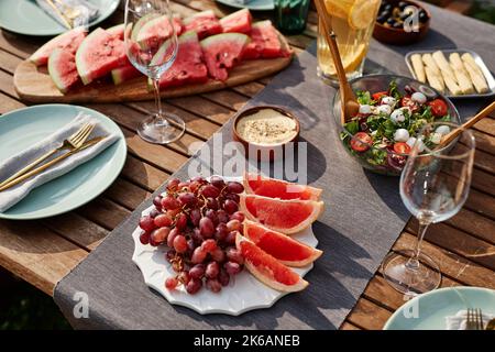 Close up of fresh fruits and berries assortment on picnic table set for dinner party outdoors, copy space Stock Photo