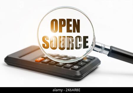 Business and finance concept. On the table is a calculator and a magnifying glass, inside which the inscription - Open Source Stock Photo