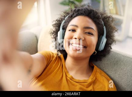 See yourself through my eyes. a young woman taking a selfie while listening to music at home. Stock Photo