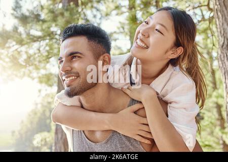 This is what boyfriends are for. a handsome young man giving his girlfriend a piggyback ride during a day in the woods. Stock Photo