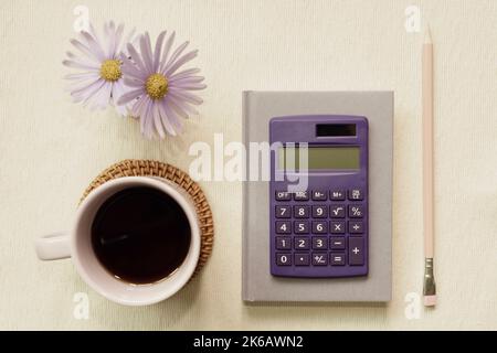 Purple supplies. notebook, calculator, colored pencil, cup of coffee, flower on desk. flat lay, top view Stock Photo