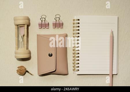 Pink supplies. Sandglass, pouch, clip, notebook, colored pencil on desk. flat lay, top view Stock Photo