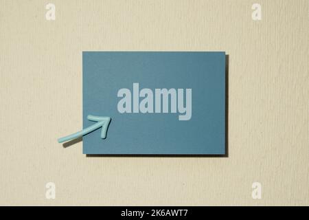 Blue memo pad and arrow on beige background. top view, copy space Stock Photo