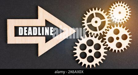 Business and finance concept. On a black background, gears and an arrow with the inscription - DEADLINE Stock Photo
