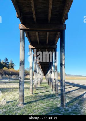 a tall bridge footbridge pedestrian path overcrossing boardwalk dry lake riverbed mountain hiking walking trail exercise healthy wooden plank structure Stock Photo