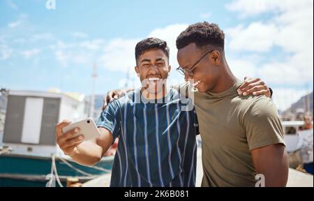 A friend is someone who makes it easy to believe in yourself. two young men taking selfies together outdoors. Stock Photo