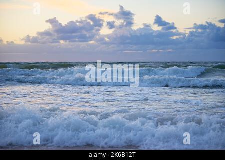 Panoramic view of sea beach with splashing waves against dramatic cloudy sky. Baltic sea coastline at sunset Stock Photo