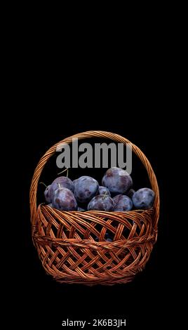 Image of a basket full of ripe plums on a black background Stock Photo