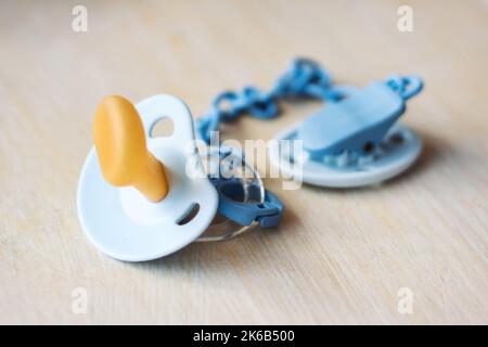 A baby's latex dummy or pacifier with a plastic chain isolated on a wooden table background Stock Photo