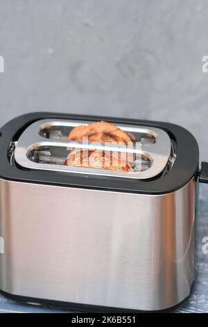A electric toaster with two pieces of toasted sliced bread. Energy use ...