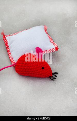 Flat lay of 2 red and white cat toys with copy space on grey Stock Photo