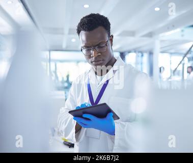 He couldnt function without his tech. a male scientist using his digital tablet. Stock Photo