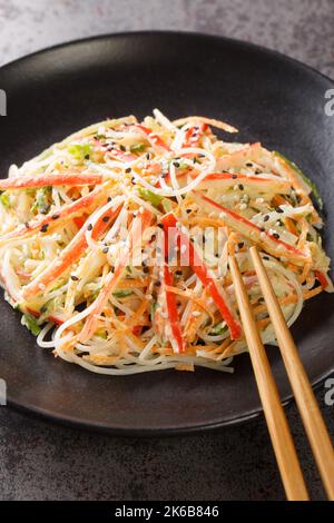 Japanese Kani Salad is a popular side dish with crunchy vegetables and savory crab sticks closeup in the plate on the table. Vertical Stock Photo